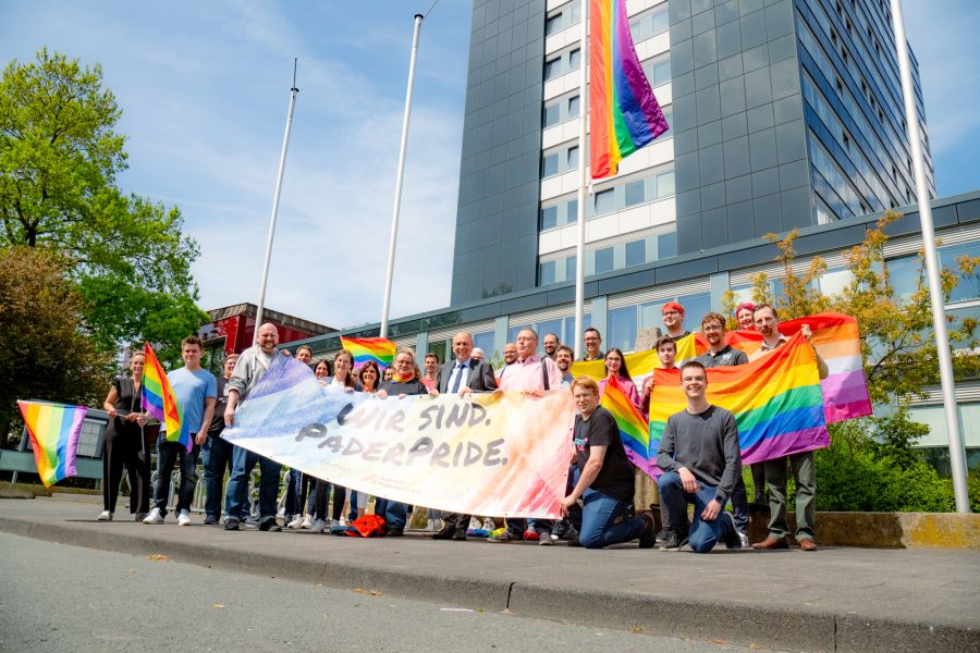 Gemeinsam und vielfältig: Mitarbeitende der Paderborner Kreisverwaltung und Vertreter der Aids-Hilfe Paderborn hissen gemeinsam mit Landrat Christoph Rüther (1. Reihe, 4.v.r.) und Gleichstellungsbeauftragte Simone Böhmer (l.) die Regenbogenfahne vor dem Paderborner Kreishaus. 